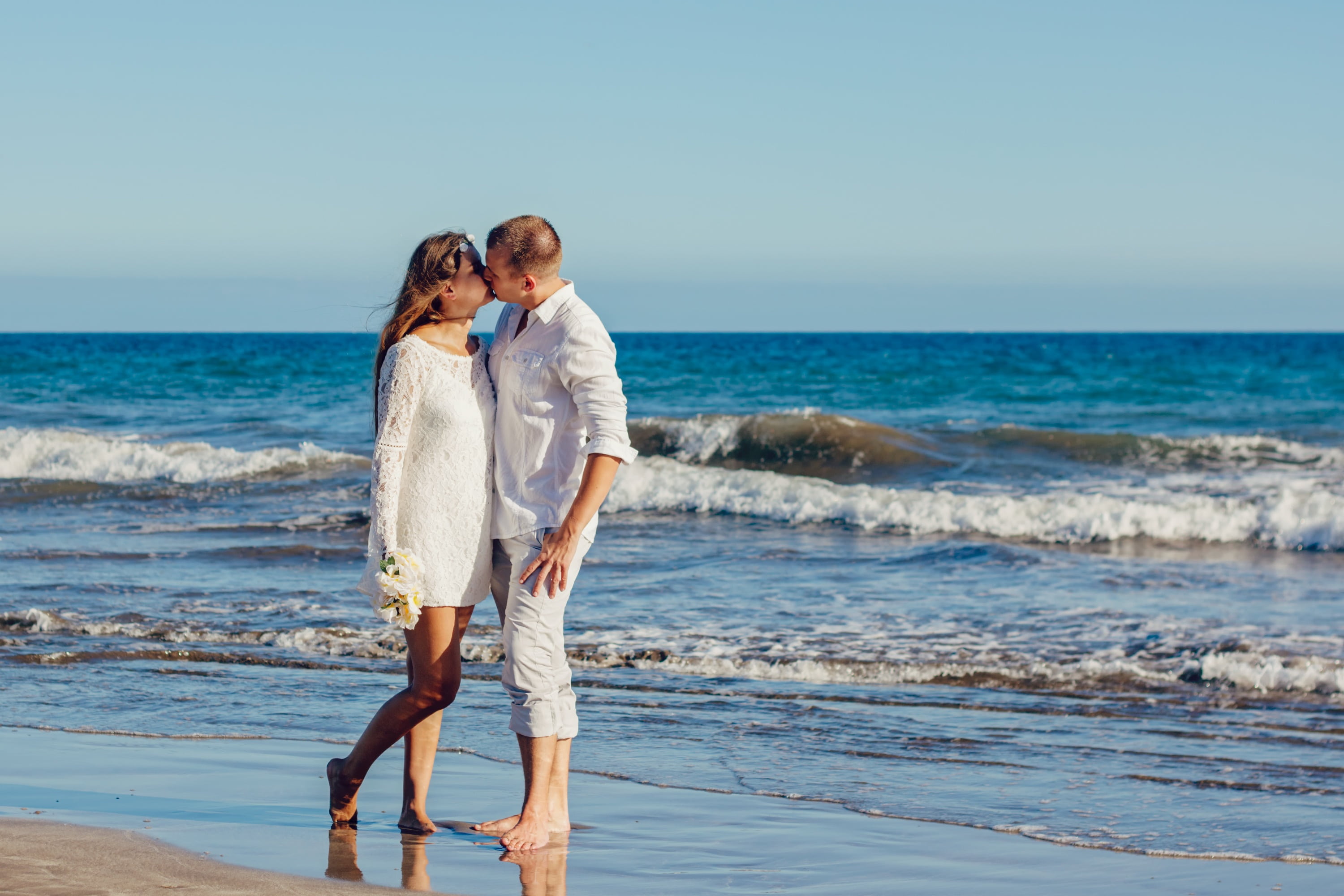woman and man standing on shoreline kissing love a couple of 2k