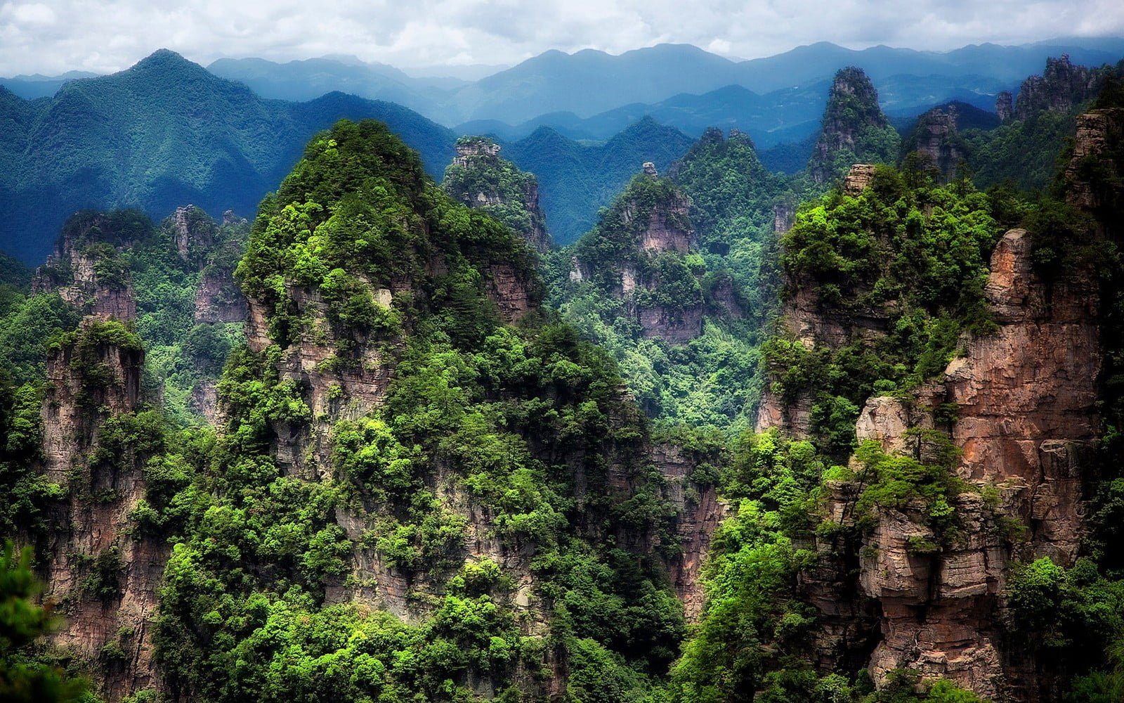aerial view photo of brown mountains with trees under cloudy sky 2k