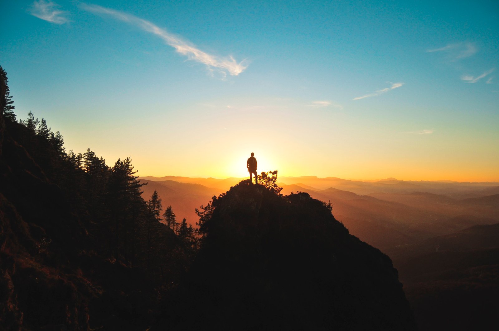 silhouette of man standing on mountain peak hill facing sunset 2k 4k