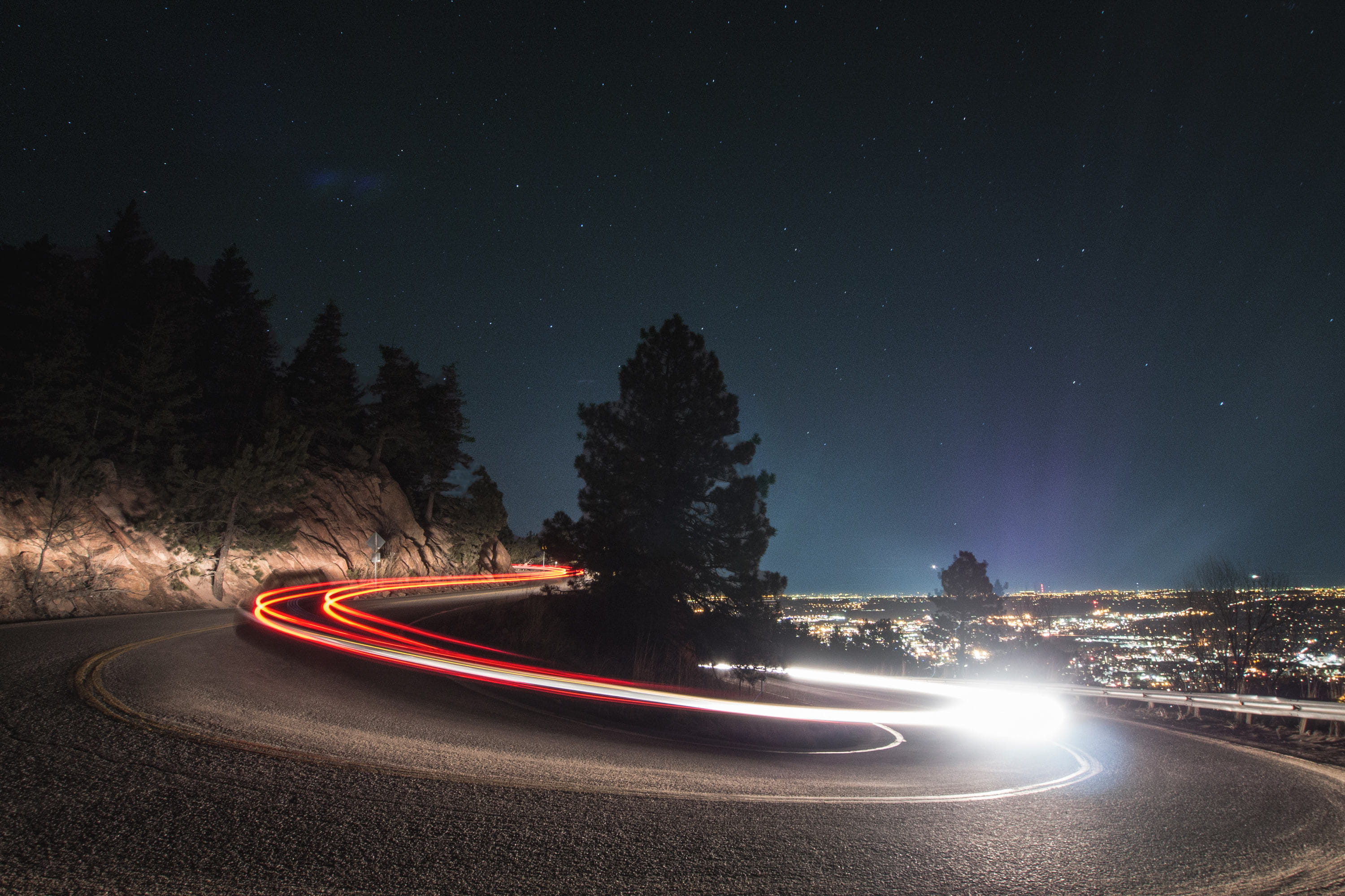 timelapse photography on curved road beside tree time lapse of vehicle lights 2k