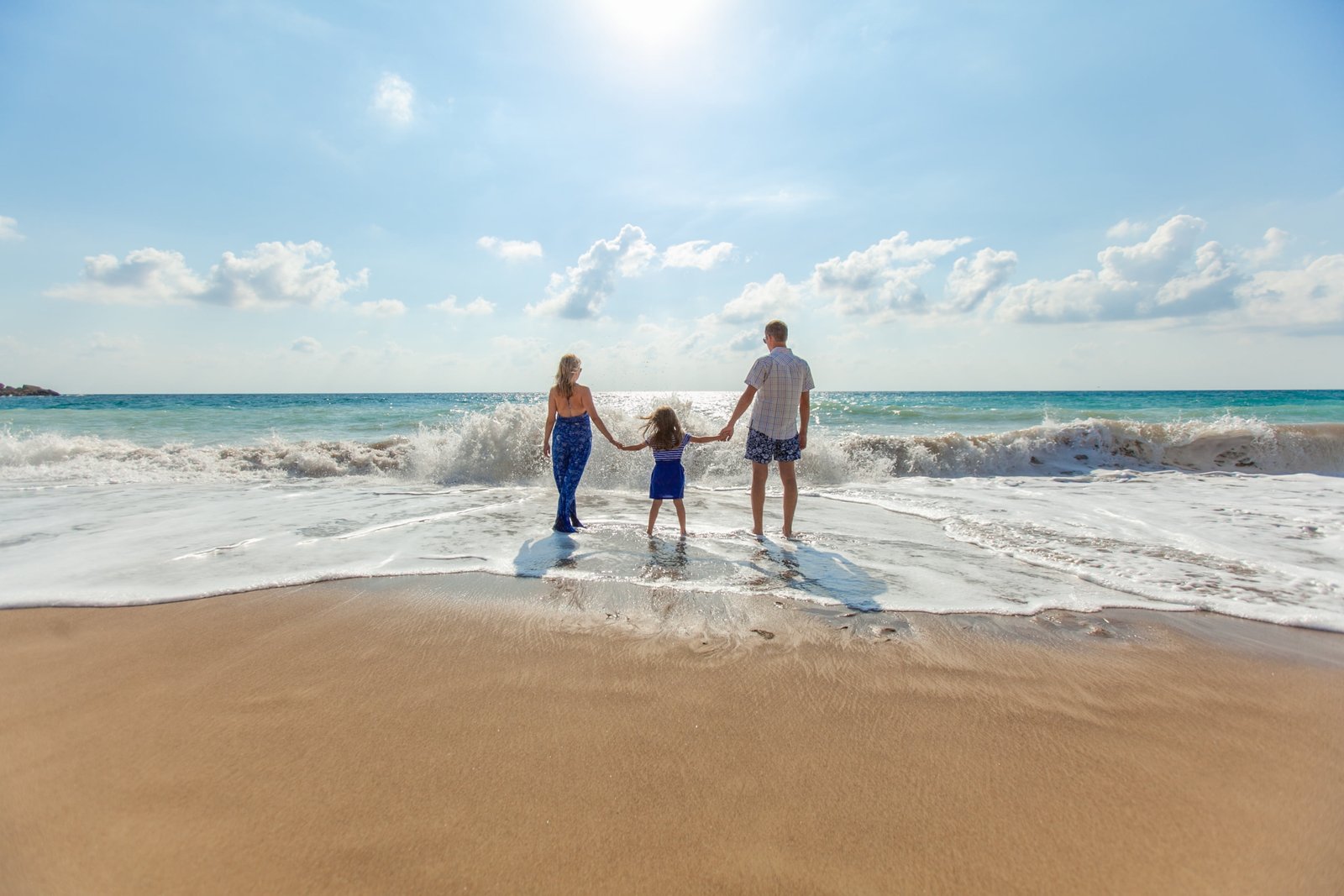 man and woman standing with their child on seashore during daytime 2k 4k