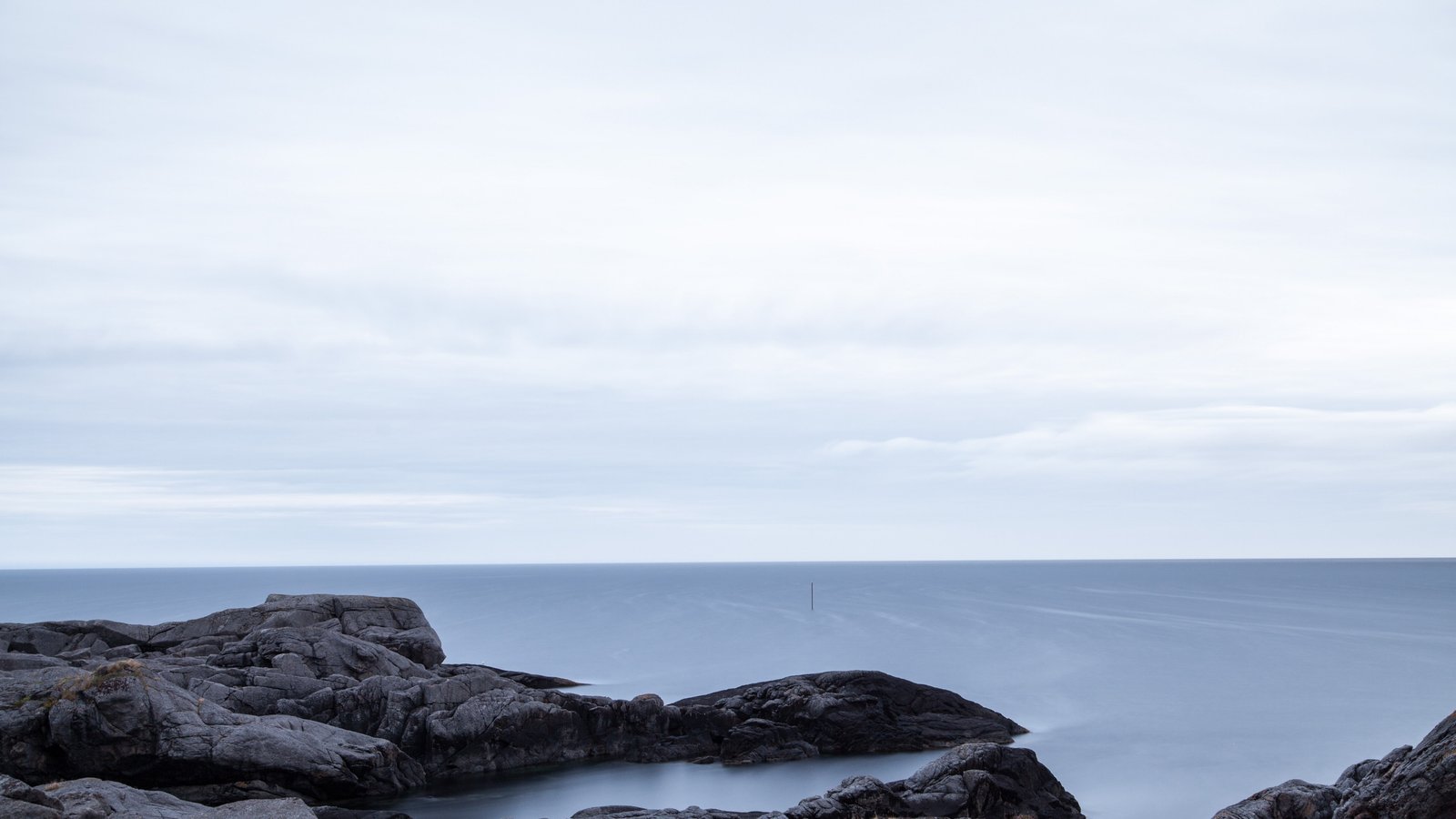 black rock formation in blue body of water under cloudy sky during daytime 2k 4k 5k