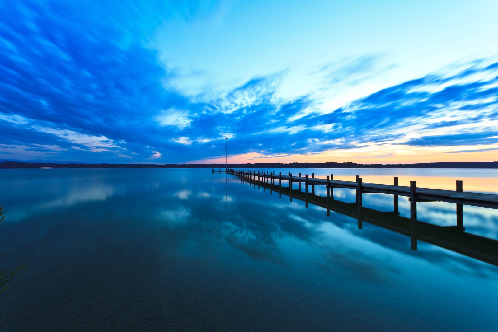 black lake dock on placid body of water under stratus clouds during golden hour 2k 4k 5k