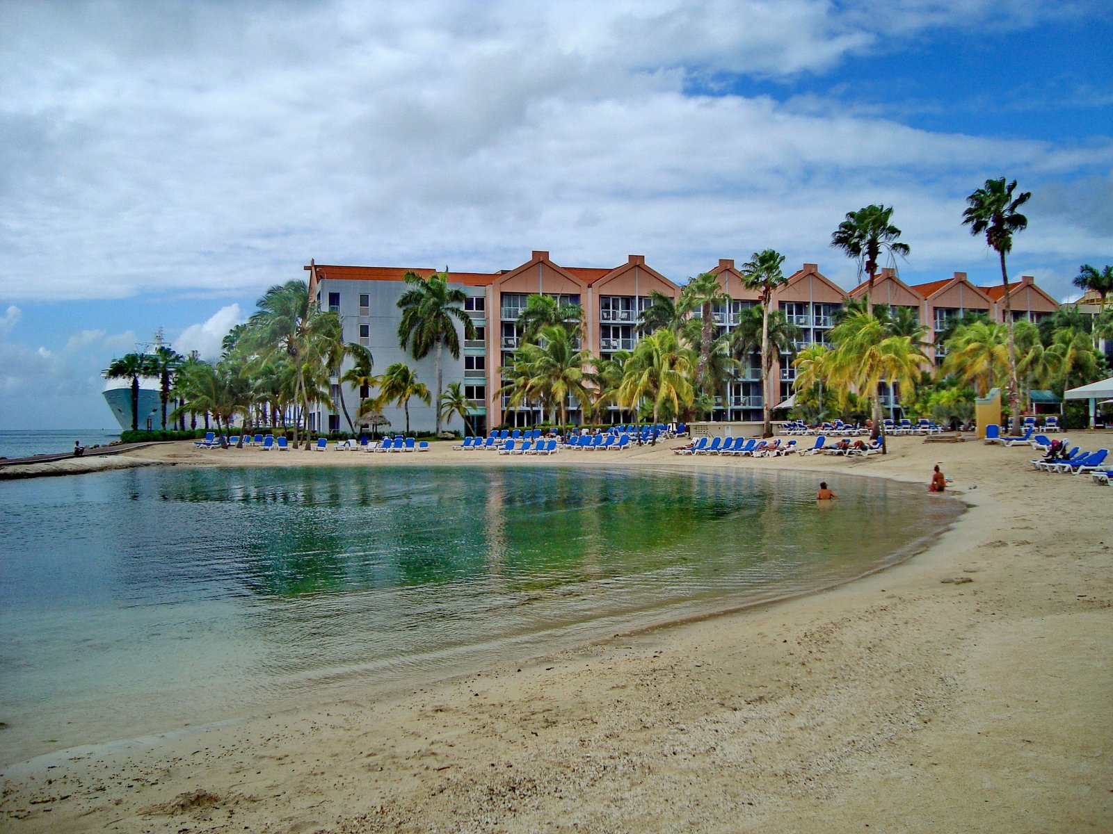 blue beach lounge near white and red buildings Aruba island 2k