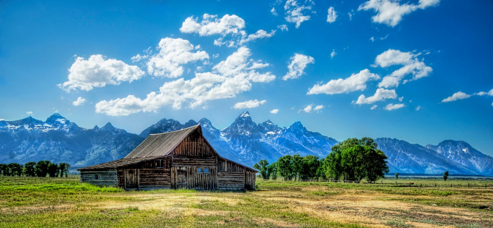 brown wooden house on middle of green grasses photo during daytime wyoming 2k 4k