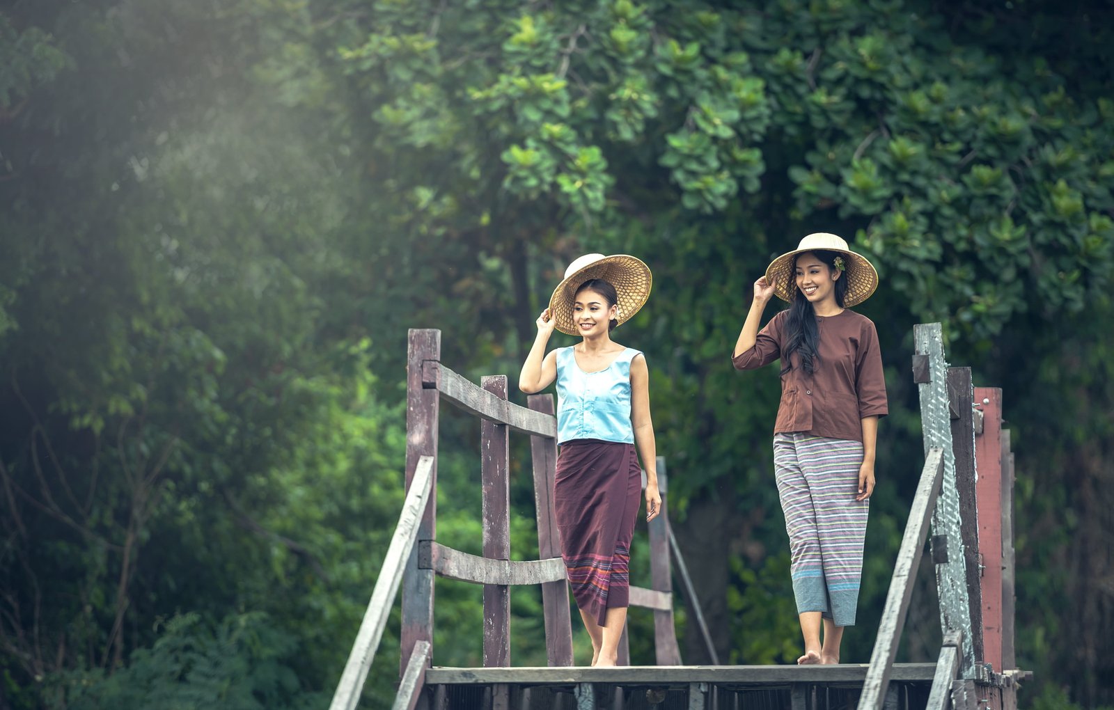 two women with hat walking on gray wooden bridge during daytime 2k 4k 5k