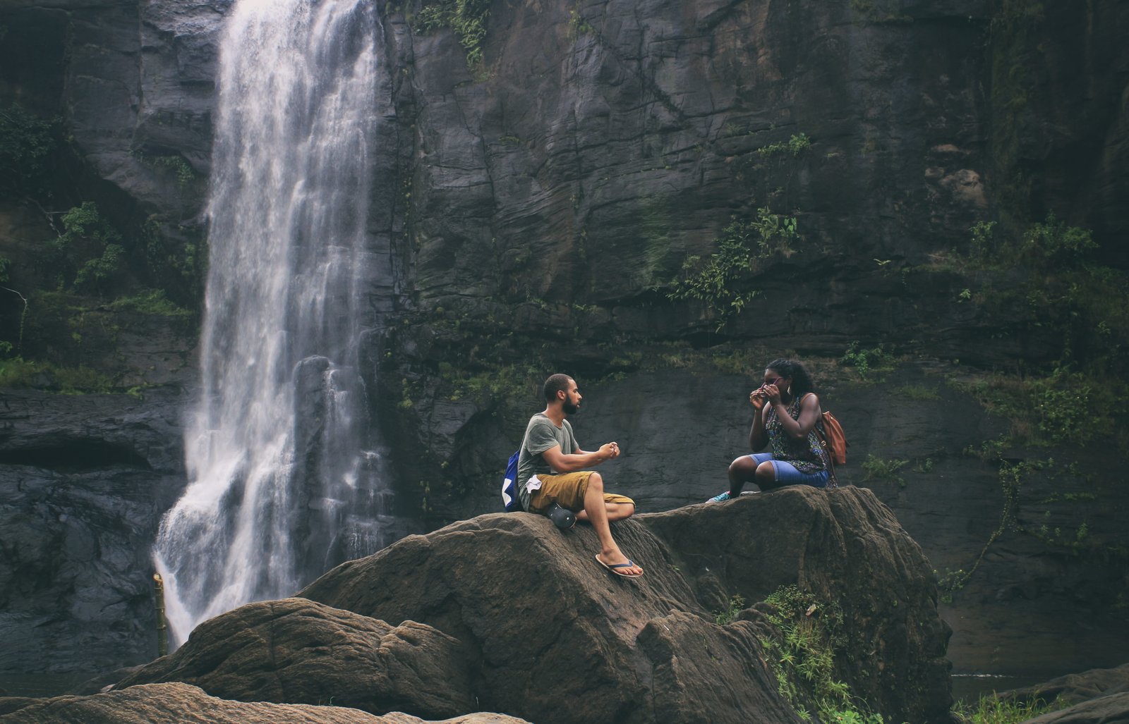 people sitting on rock near waterfalls Love Couple Woman young 2k 4k 5k