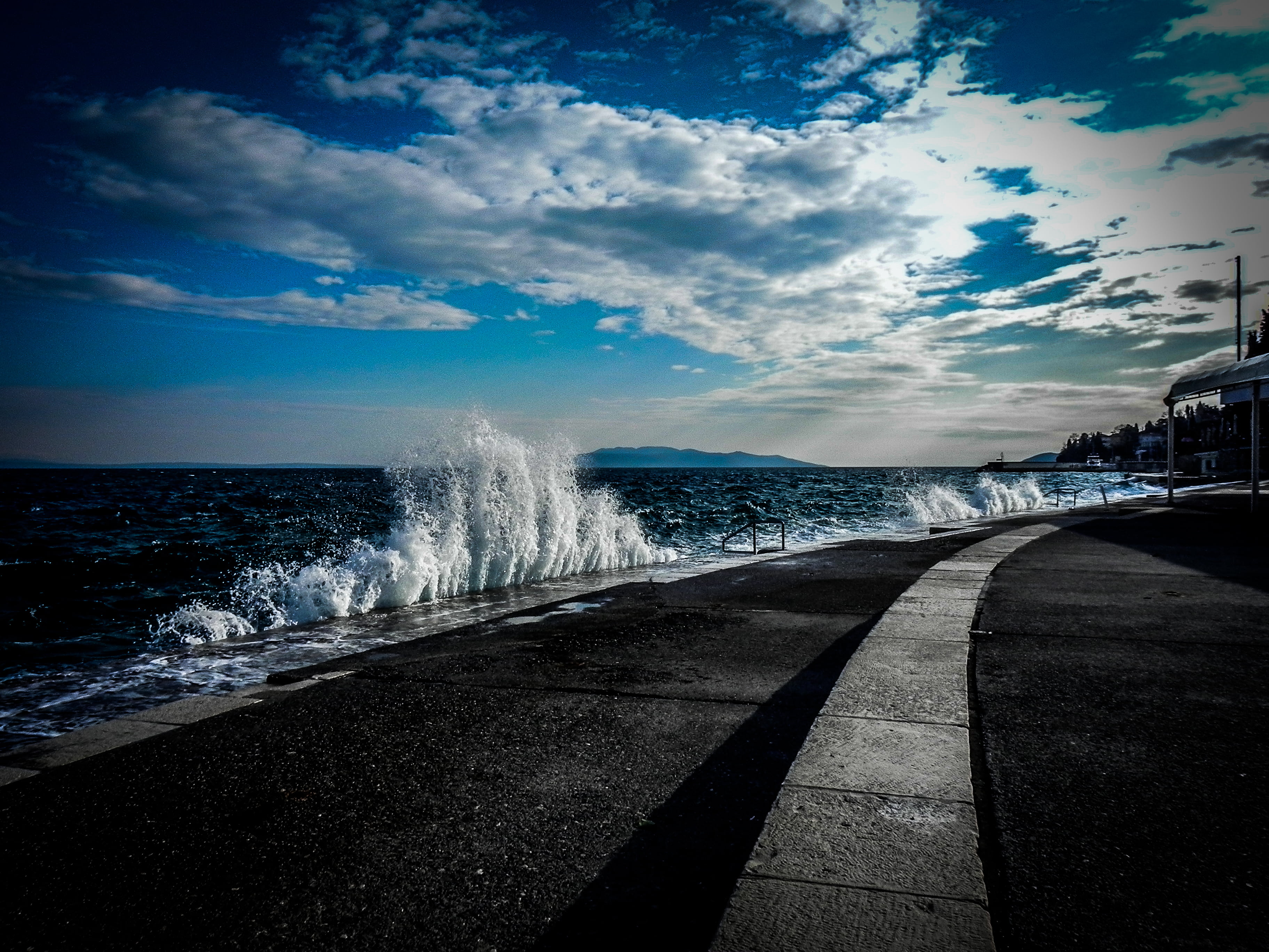 gray concrete road near the ocean water during daytime Waves 2k 4k