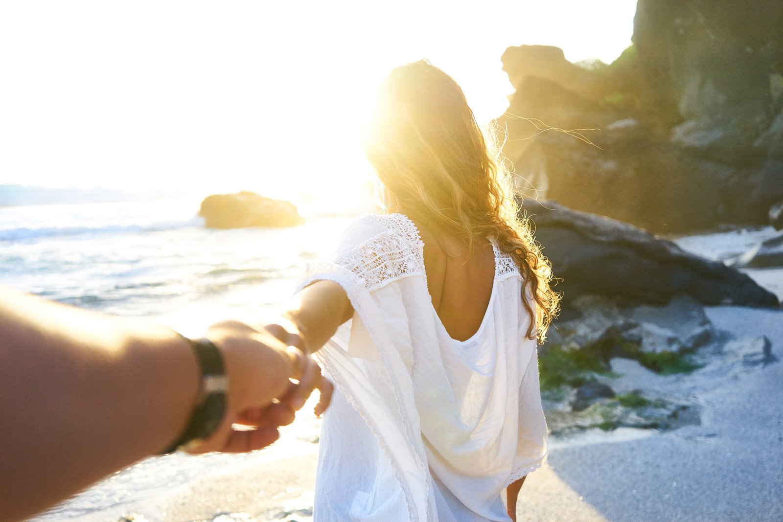 person holding woman s hand beside sea while facing sunlight a on seashore 2k 4k 5k