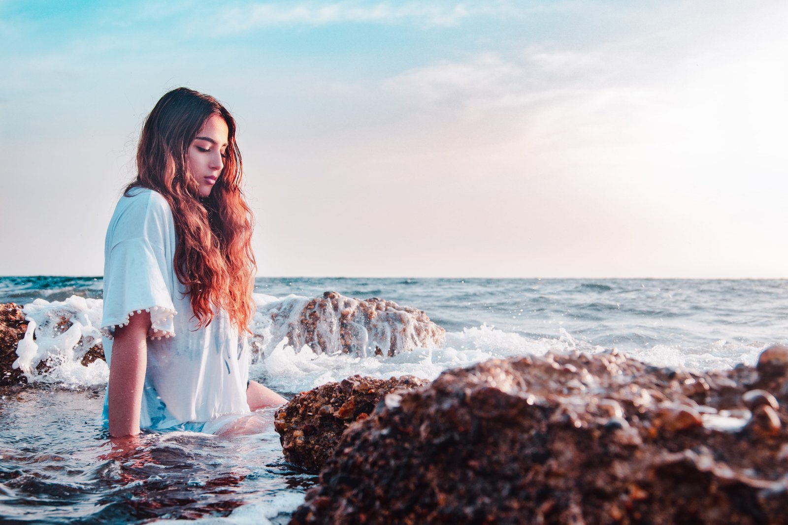 woman sitting at the rocky shore on seashore beside stones 2k 4k 5k