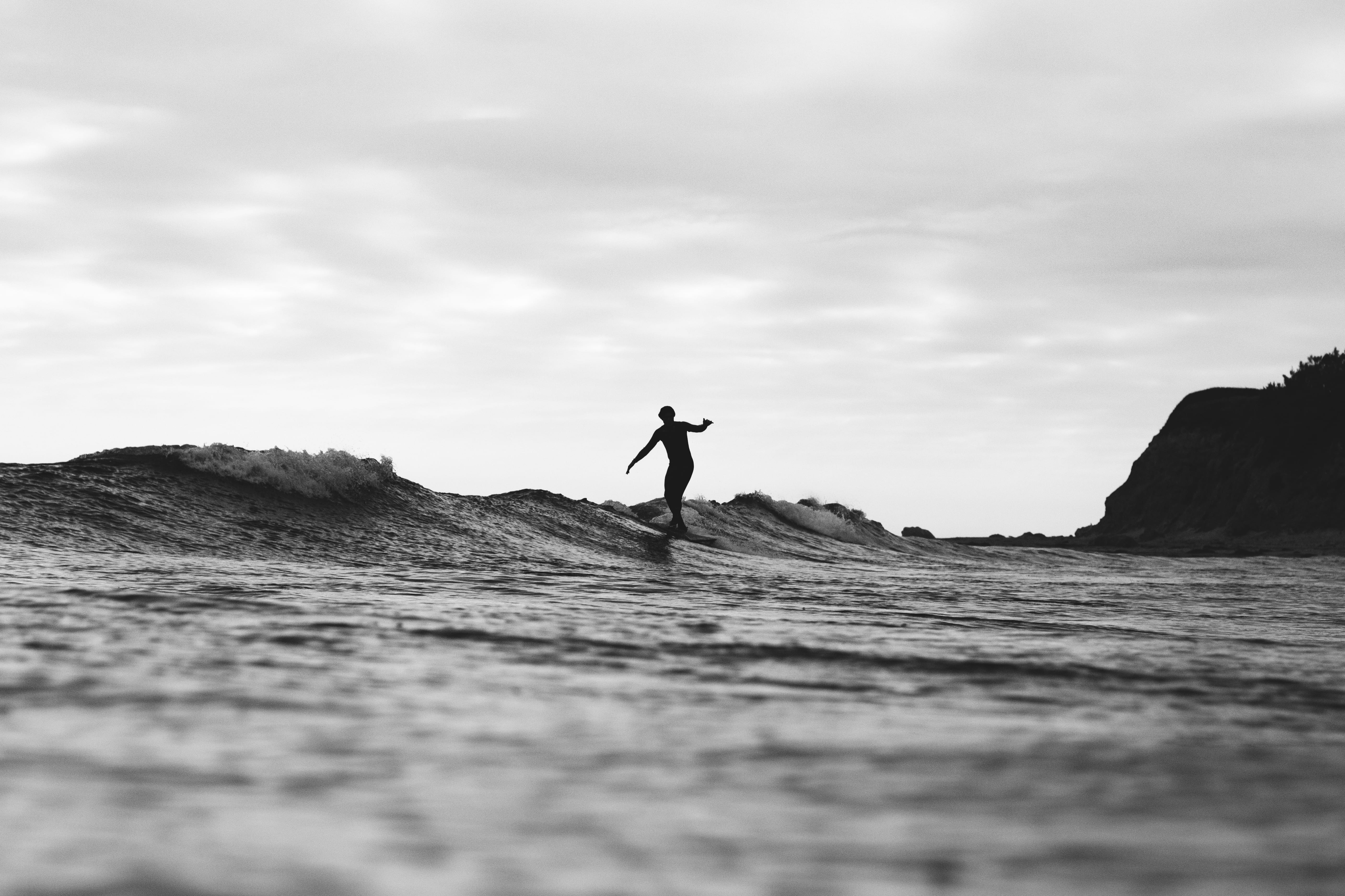grayscale photography of person surfing on sea silhouette man riding surfboard 2k 4k 5k