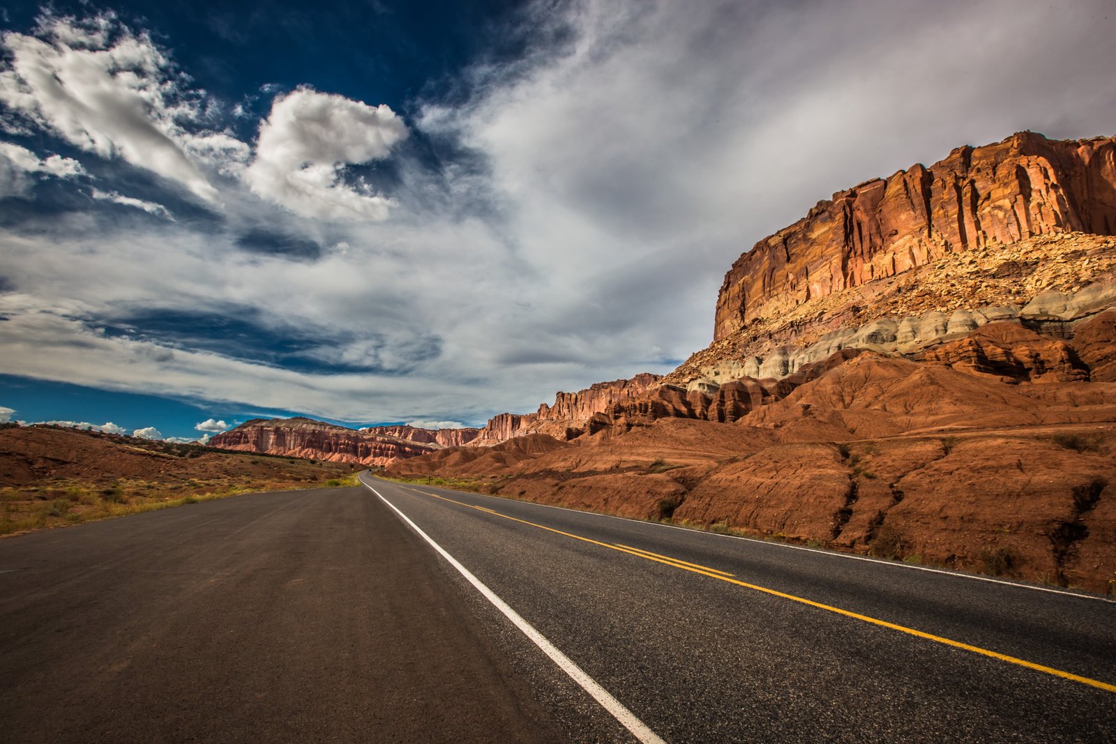 brown concrete roadway near mountain under white clouds at daytime 2k 4k 5k