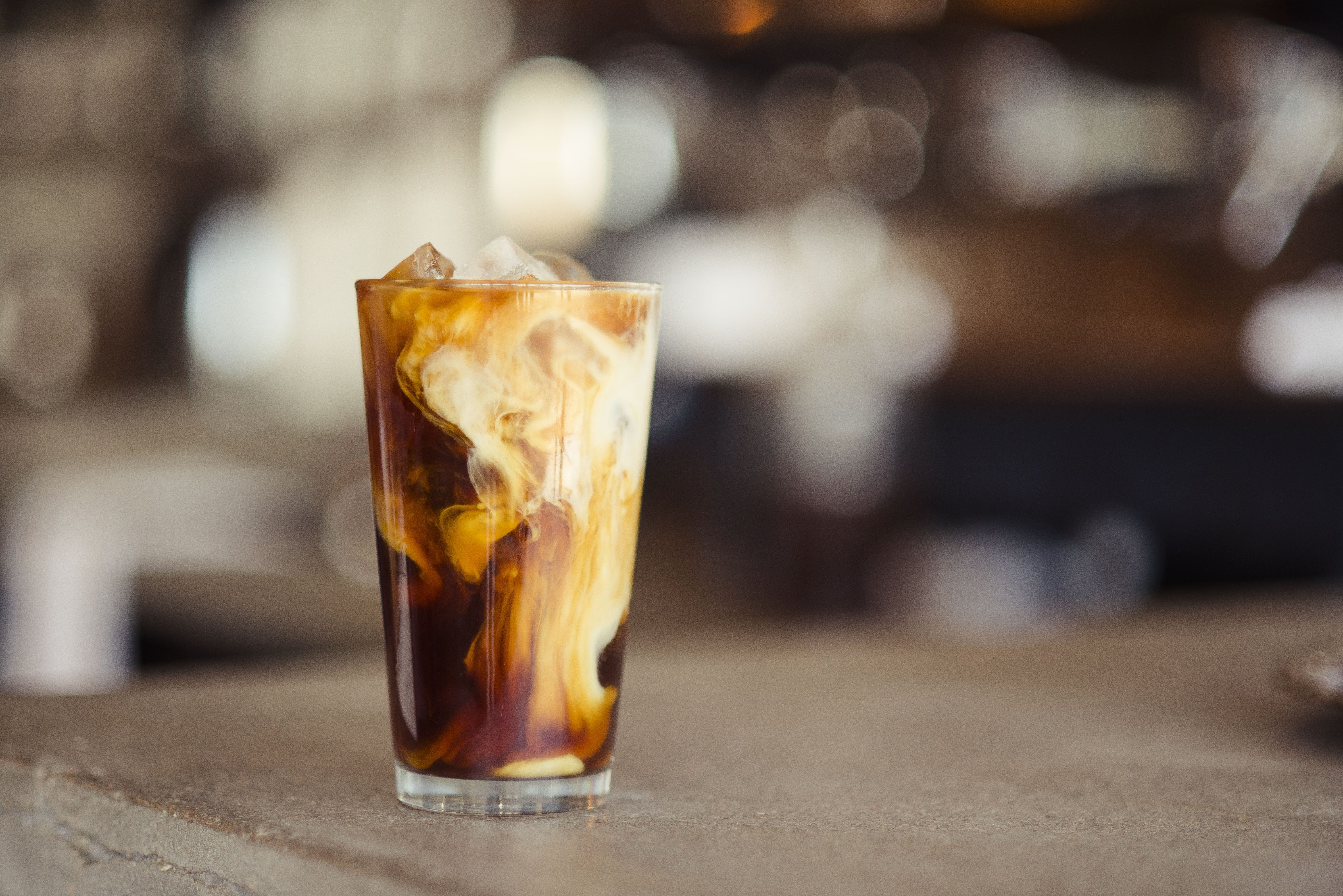 glass cup filled with ice latte on tabletop tilt shift photography of iced coffee 2k 4k 5k