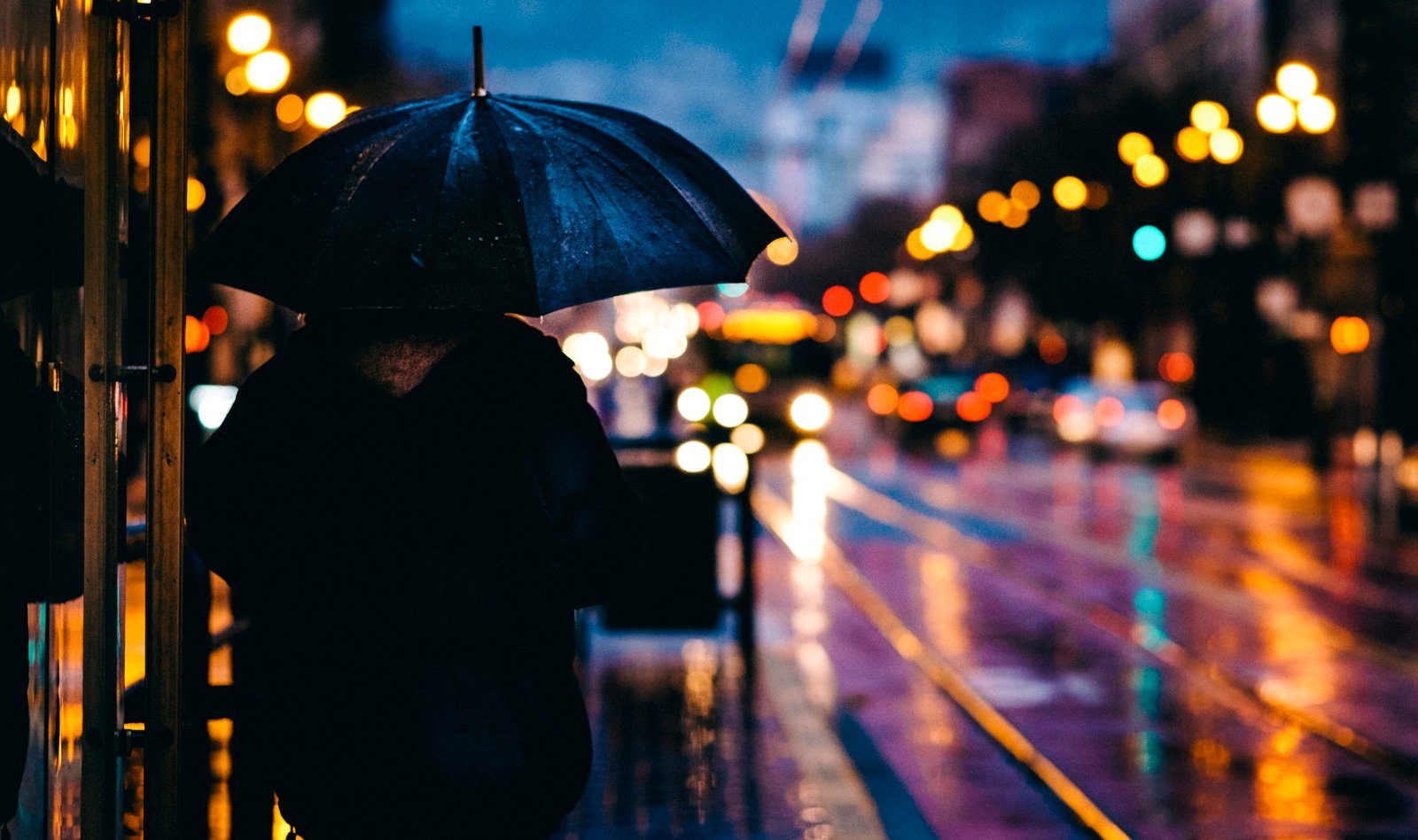 person walking on street while holding black umbrella near cars road at nighttime 2k 4k