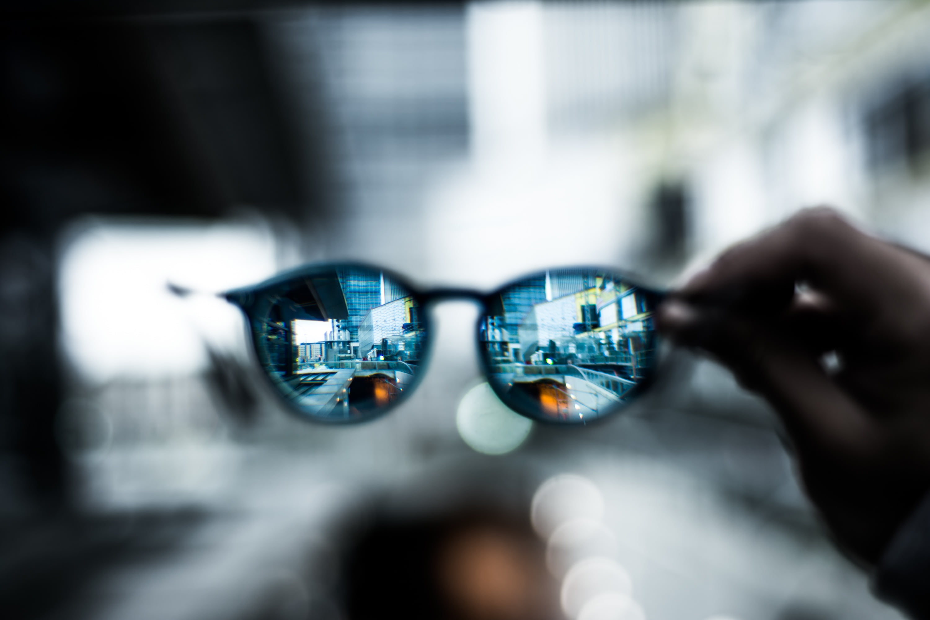 selective focus photography of person holding Clubmaster style sunglasses 2k