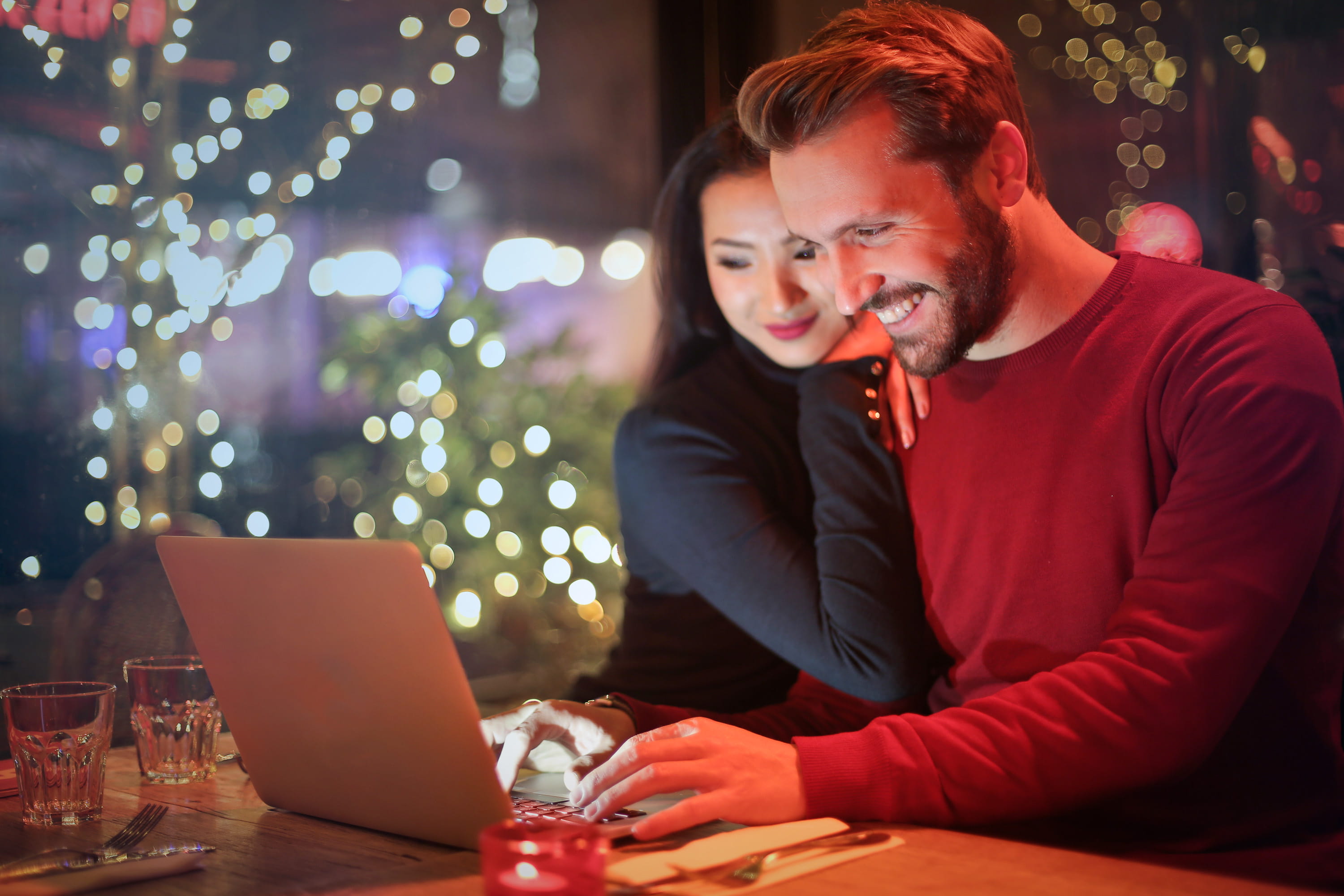 Young couple surfing on internet with laptop during romantic dinner in a restaurant 2k