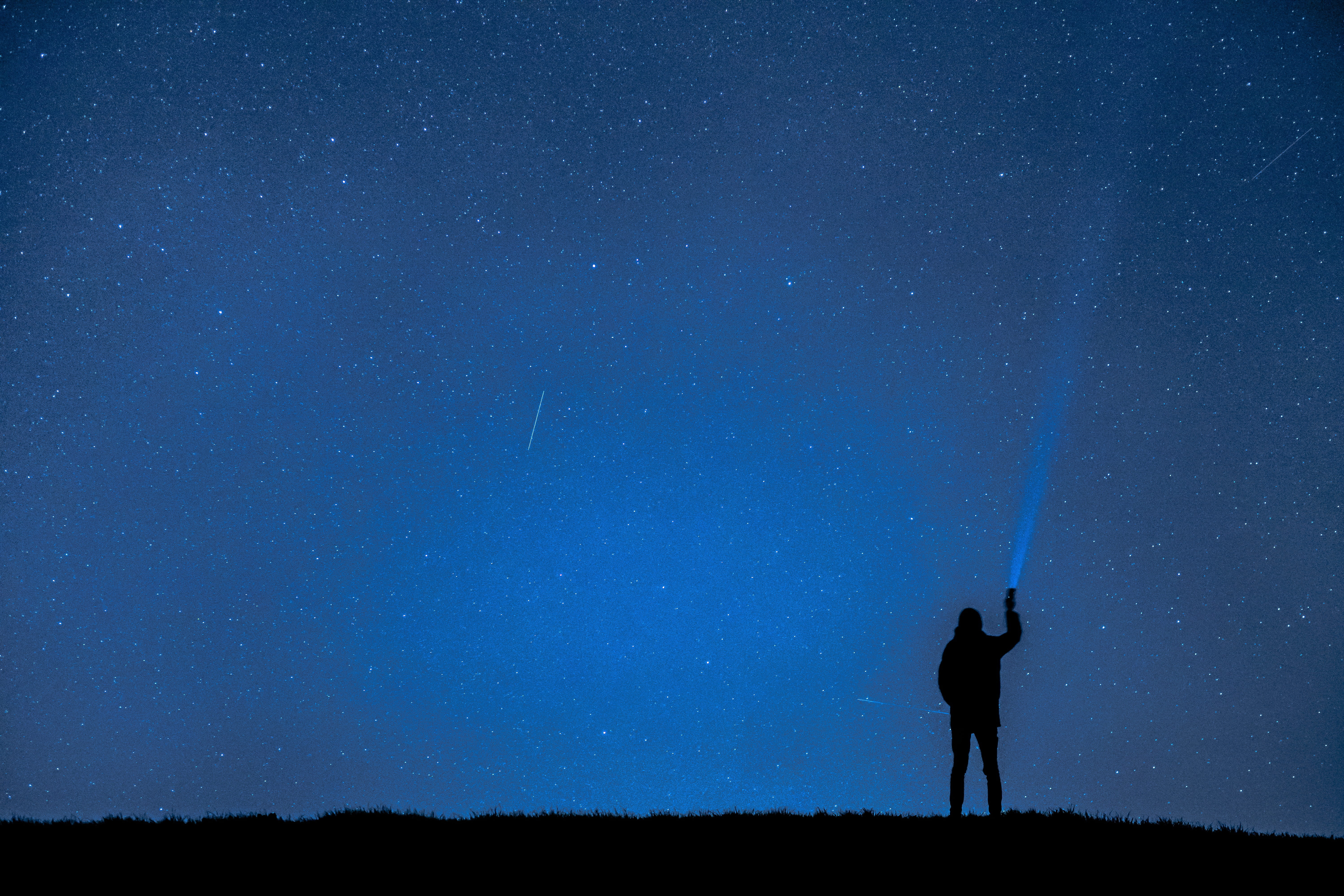 person silhouette holding flashlight on blue sky night photograph 2k 4k 5k