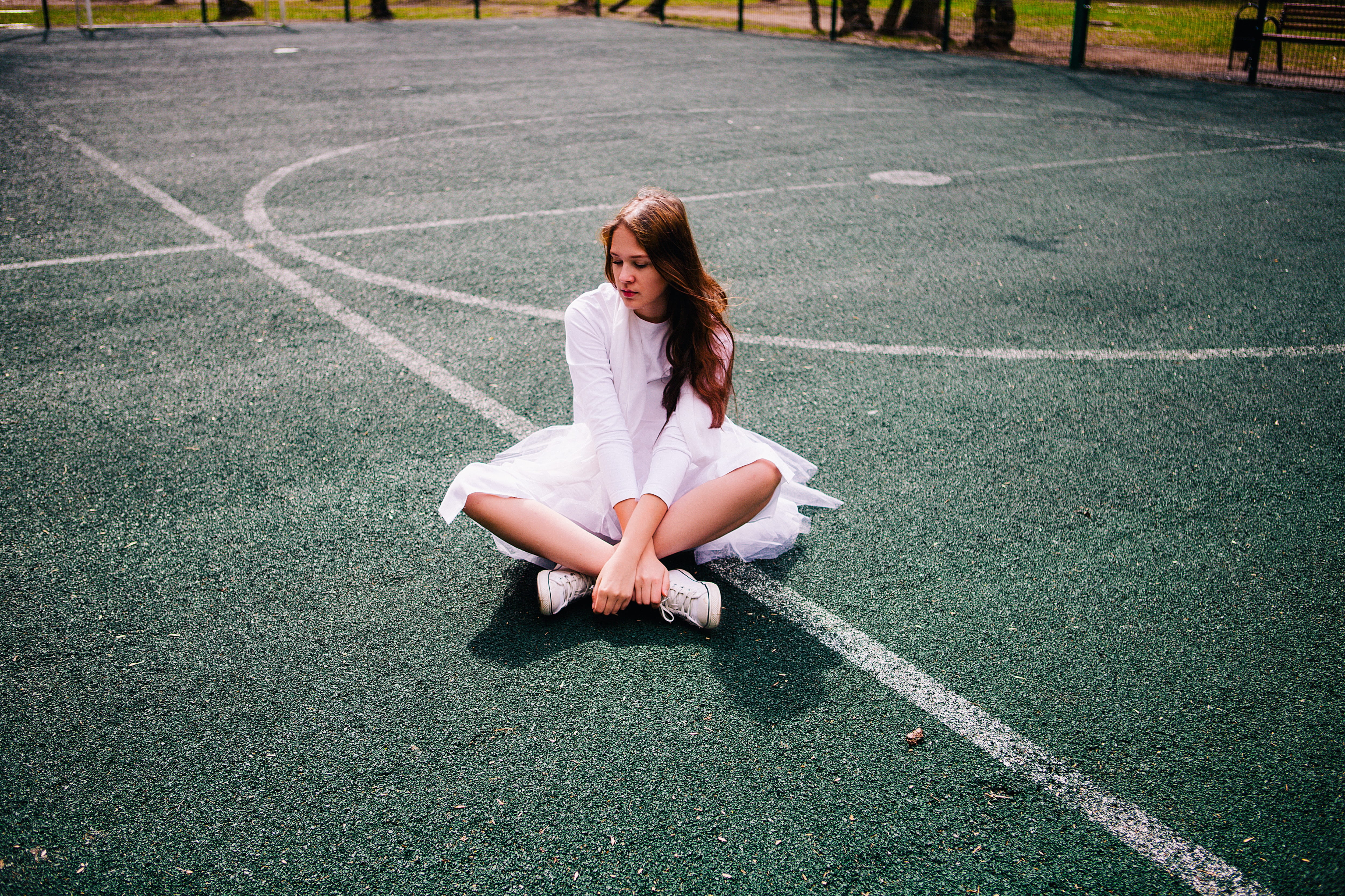 woman wearing white dress sitting on basketball court during daytime 2k 4k 5k